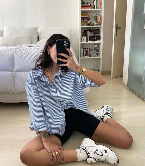 a blue thin stripe oversized shirt, black biker shorts, black and white trainers and white socks for every day