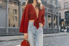 a bold look with a burgundy knotted crop top with long sleeves, high waisted cropped jeans, red shoes and a burgundy bag