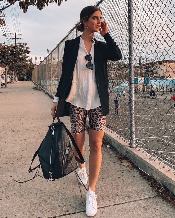a bold summer outfit with a white shirt, a black blazer and a backpack, leopard print shorts, white sneakers