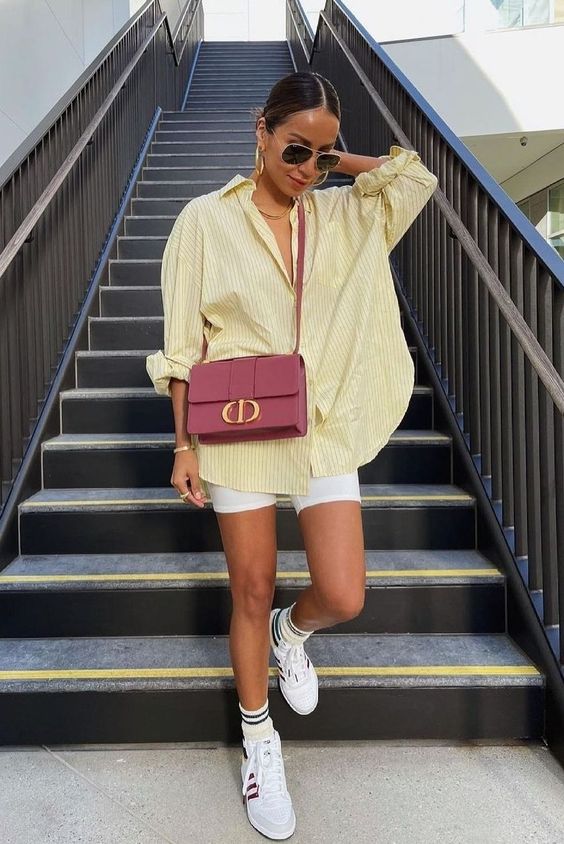 a bright summer look with an oversized yellow striped shirt, white biker shorts, white sneakers and socks, a mauve bag