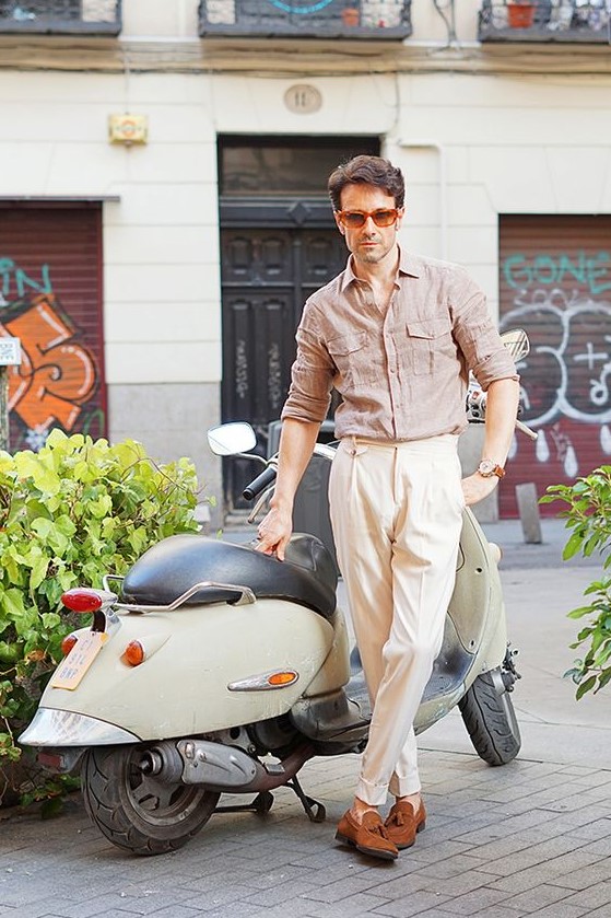 a cool summer look with a brown linen shirt, neutral trousers, rust colored moccasins and sunglasses in a red frame