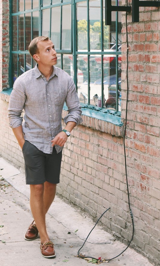 a grey linen shirt, graphite grey shorts and brown boat shoes for a comfortable summer look