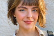 a layered bob with brighter locks and small, baby bangs looks super cute and very young