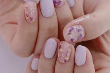 a lovely spring manicure with pale pink and blush nails, blush ones are accented with purple and blush dried blooms and gold touches