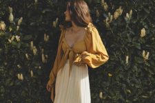 a lovely summer look with a mustard-colored knotted crop top with puff sleeves and a creamy pleated midi is a very feminine idea