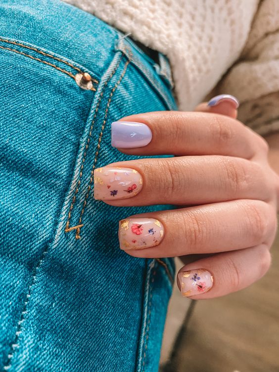 a nude and lilac manicure with nude nails accented with gold leaf and colorful dried blooms looks veyr spring-like