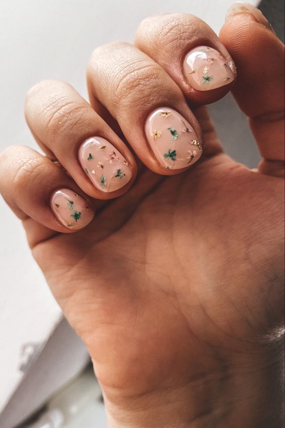 a nude manicure accented with neutral and green dried flowers look delicate and nature-inspired and will give a natural feel to your look
