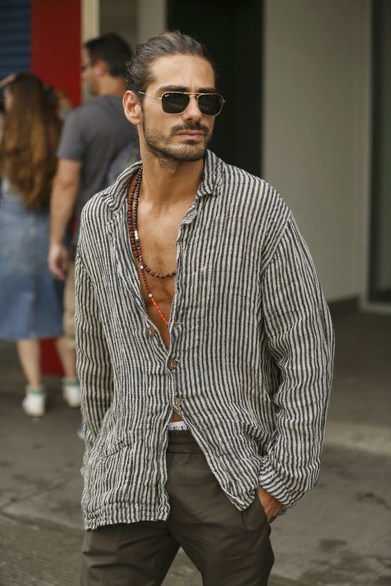 a relaxed vacation look with a striped linen shirt, grey pants, layered beaded necklaces and sunglasses