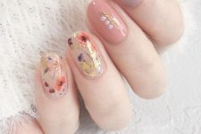a romantic pastel manicure with a lilac, coral and blush nails, blush ones are accented with colorful dried blooms