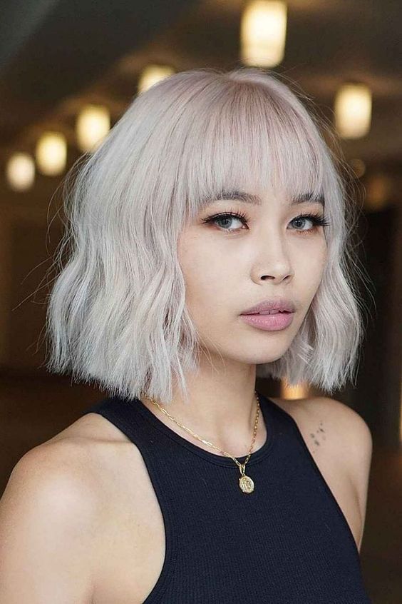 a short icy blonde layered bob with bangs and a bit of waves is a bold and cool idea to stand out
