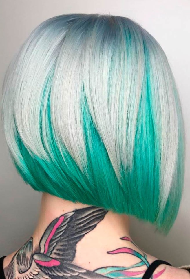 a stacked and layered bob with bold color, with a light blue root going to icy blonde and then to emerald