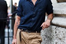 a stylish summer look with a navy linen shirt, tan pants, a black belt and a printed bag is a cool idea