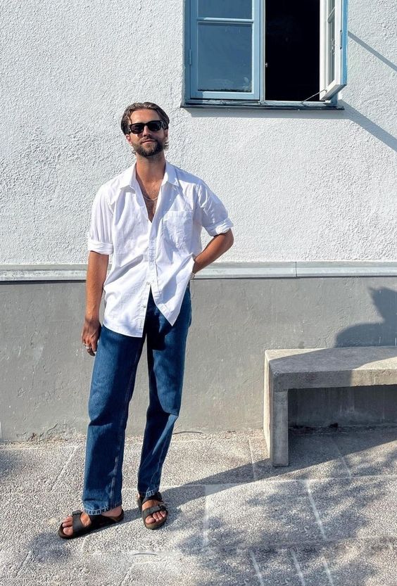 a summer outfit with a white linen shirt with cuffed sleeves, blue jeans and grey birkenstocks is breathable and cool