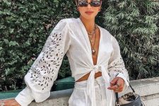 a vacation look with a white linen knotted crop top with puff sleeves, high waisted linen shorts and a black bucket bag