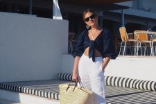 a vacation outfit wiht a navy wrap top with puff sleeves, white linen pants, brown slippers and a woven bag