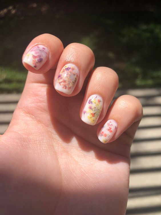milky nails with colorful dried flowers are a gorgeous idea for a spring or summer look, they can be rocked at a wedding, too