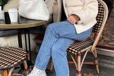09 a black turtleneck, a creamy faux fur jacket, blue jeans, white sneakers and a creamy woven clutch is cool