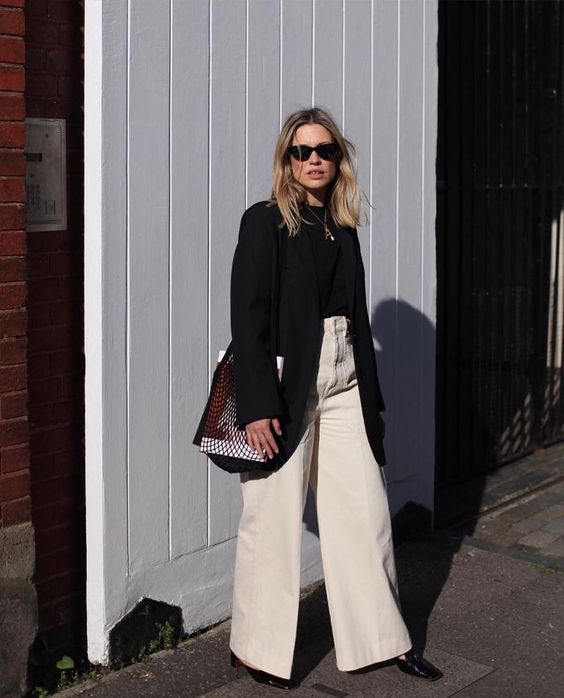 a fall work look with a black turtleneck and an oversized blazer, white wideleg jeans, black shoes and a woven bag