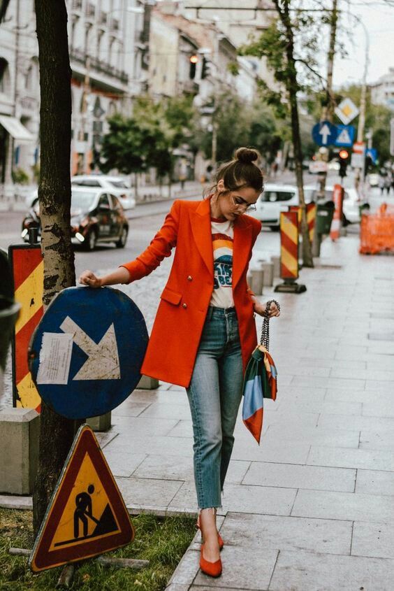 blue cropped jeans, a printed t shirt, red shoes, an oversized red blazer and a bag with a colorful handkerchief