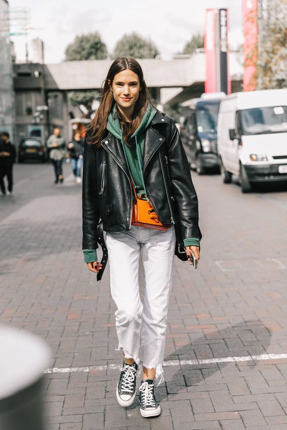 a green hoodie, white jeans, black sneakers and a black leather jacket for a cool fall look