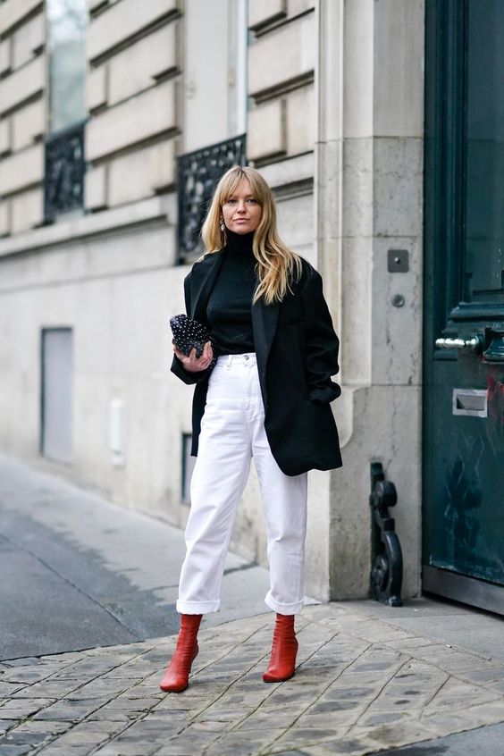 a contrasting outfit with a black turtleneck, a black oversized blazer, white jeans, red boots and a small black bag