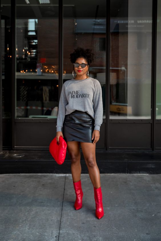 a grey sweatshirt, a black leather mini, red boots and a hot red bag plus hoop earrings for a date