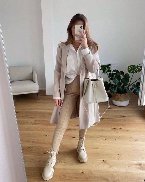 a neutral work outfit with a white shirt, tan trousers, an off-white trench, creamy combat boots and a creamy bag