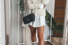 25 a white mini shirtdress, a white jumper over it, white chunky Chelsea boots, white socks and a small black bag