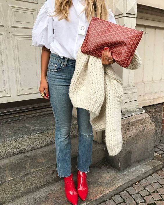 a white shirt with puff sleeves, blue cropped jeans, hot red booties, a chunky knit creamy jumper and a large clutch