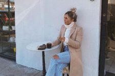 31 a white turtleneck sweater, blue ripped jeans, creamy combat boots, a tan coat and a small bag
