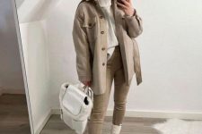 32 a white turtleneck sweater, grey leggings, white chunky boots, a tan shirt jacket and a white backpack