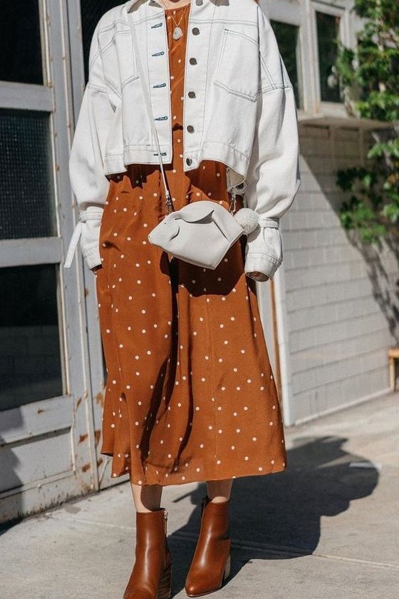 a rust colored polka dot midi dress, a white denim jacket, a white mini bag, brown boots for fall