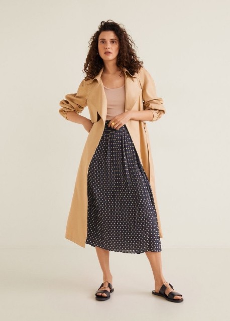 With beige top, beige midi trench coat and black leather flat sandals