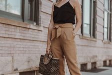 With black sleeveless loose top, oversized sunglasses, white heeled shoes and tote bag