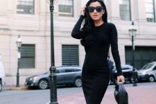 With oversized sunglasses, black leather mini bag, black long sleeved fitted shirt and black and transparent pumps