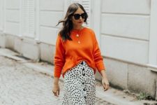 With oversized sunglasses, orange loose sweater, golden necklace and black leather high boots