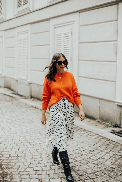 With oversized sunglasses, orange loose sweater, golden necklace and black leather high boots