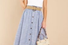 With oversized sunglasses, white sleeveless top, beige belt, beige straw bag and beige leather low heeled shoes