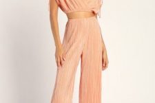 With pale pink pleated crop top and golden flat sandals