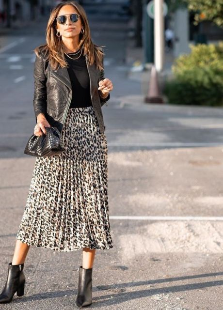 With sunglasses, rounded earrings, black shirt, black leather jacket, black clutch and black leather ankle boots