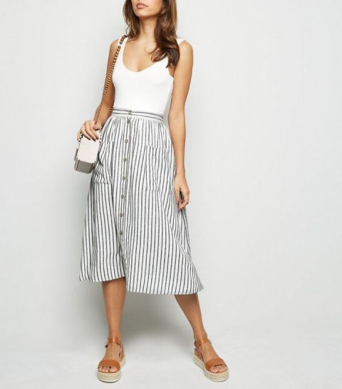 With white sleeveless top, brown leather platform shoes and white chain strap bag