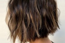 a dark brown short bob with blonde balayage and babylights, with messy waves looks eye-catchy