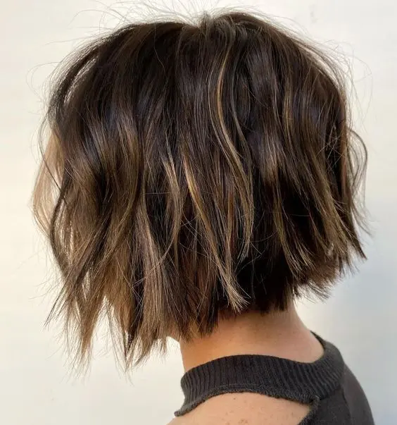 a dark brown short bob with blonde balayage and babylights, with messy waves looks eye catchy