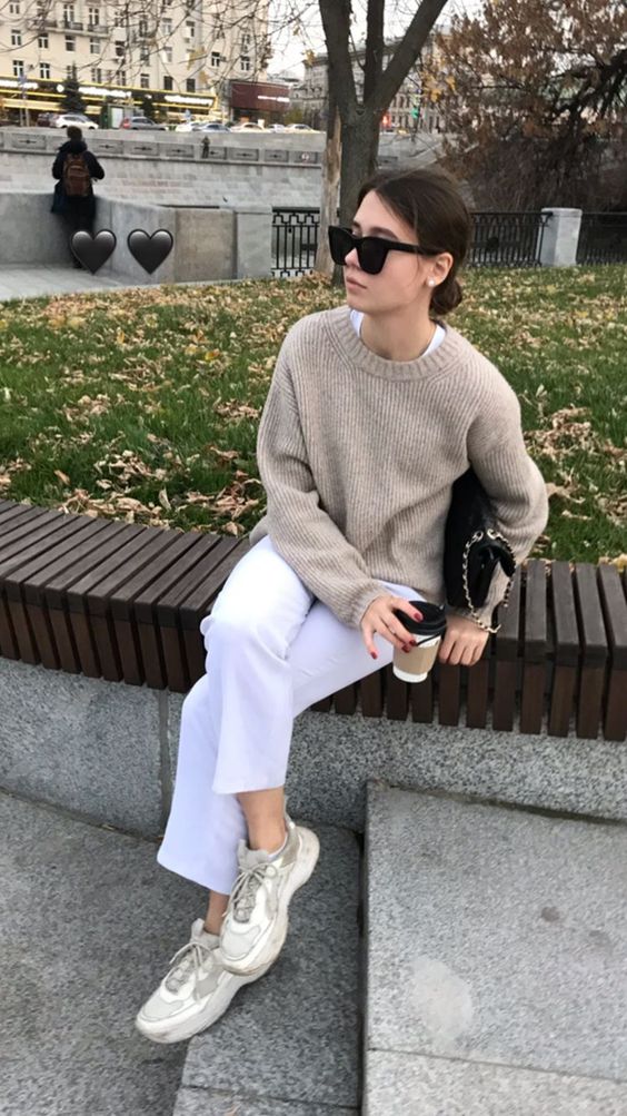a white top and white jeans, neutral trainers, a greige sweater and a black bag with chain for the fall