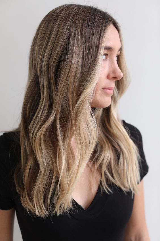 long light brunette hair with beach kissed blonde highlights and slight waves is a cool idea for a beahc-inspired look