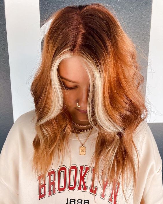 medium length copper red hair with waves and a chunky blonde money piece is a gorgeous idea for a bold look this fall