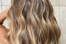 warm beach blonde hair – swept in chunky slices, the lightener creates a bold contrast against the dirty blonde roots