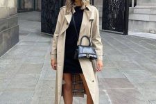 02 a black mini sweater dress, a tan trench, black chunky boots, a black bag and a black cap for a comfy look