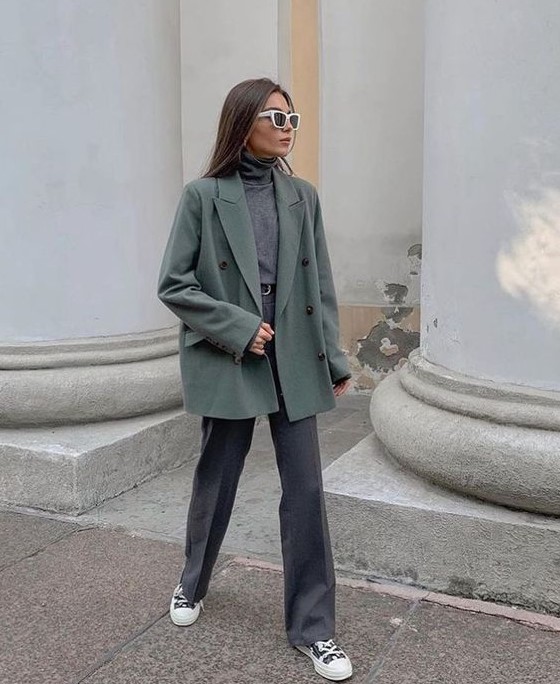 a casual work outfit with a grey turtleneck, trousers, a green oversized blazer and grey and white sneakers