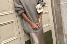 03 a chic grey fall outfit with an oversized sweater, a slip maxi skirt, white shoes and a small white clutch